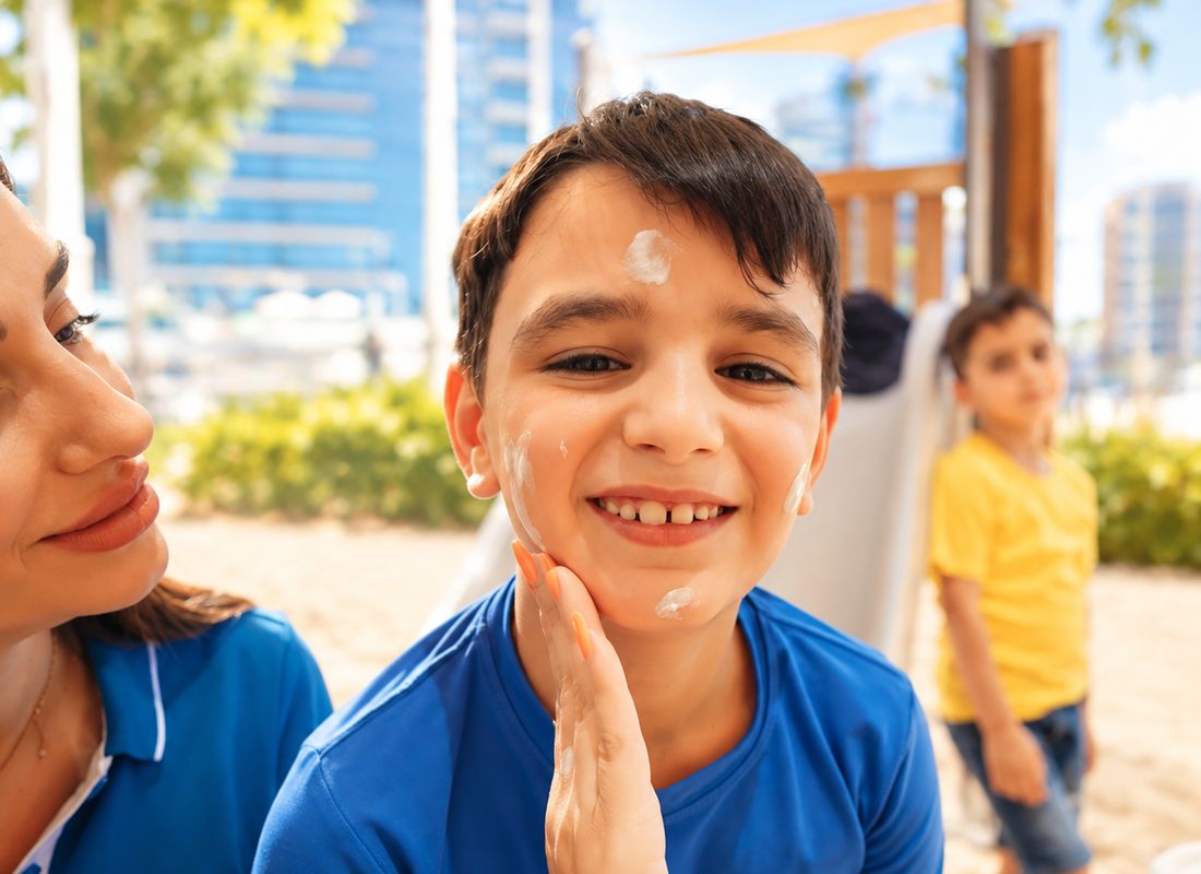Mother applying sunscreen to her smiling son outdoors – family lifestyle video production Dubai